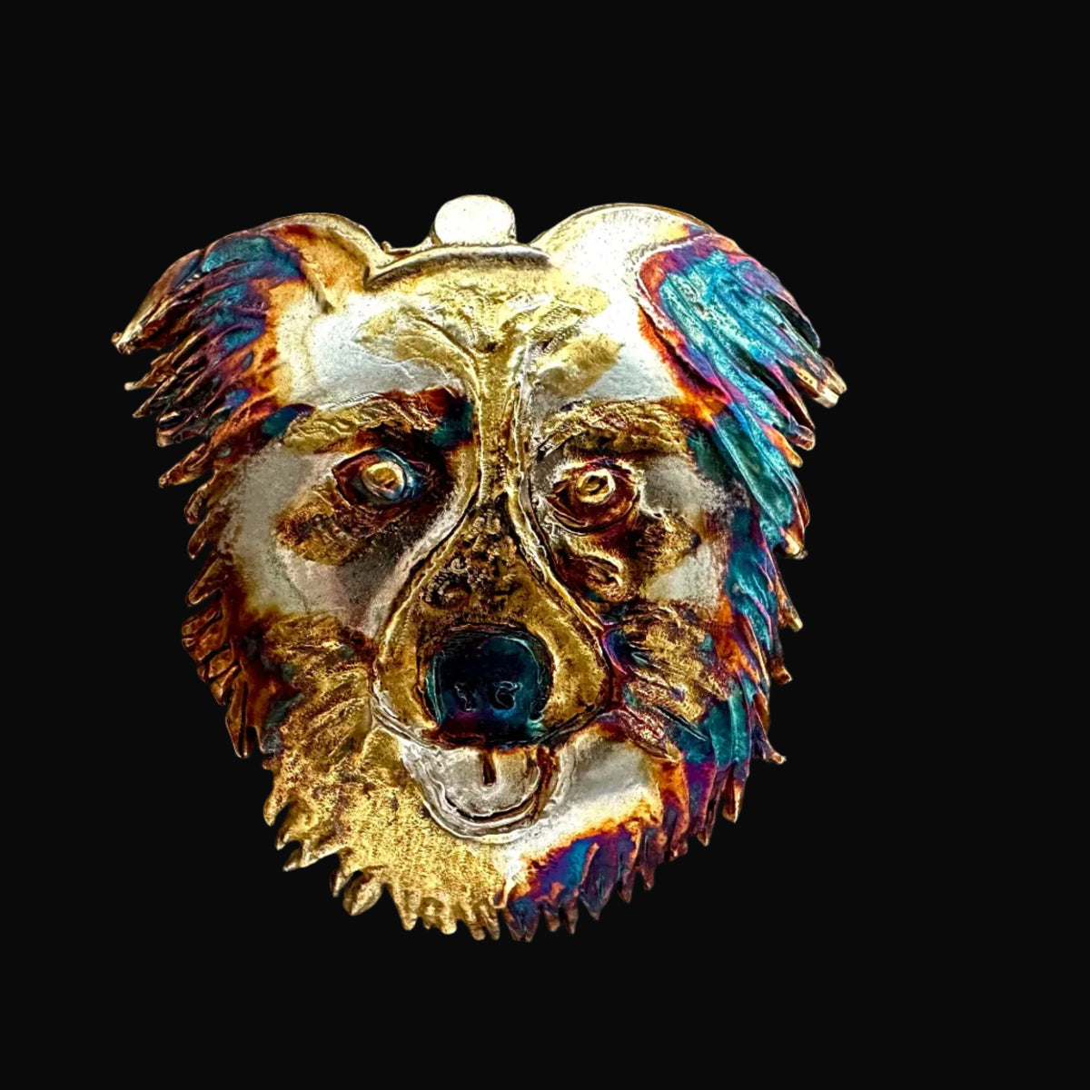 A silver dog head pendant gold-foil and iridescent multicolor patina accents in blue, purple, and orange, shown against a black background.